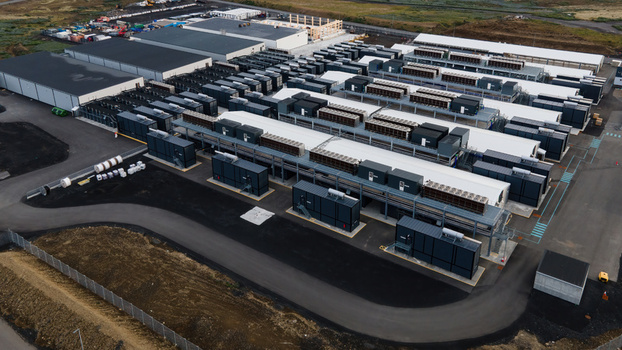 Aerial view of a large data center facility featuring rows of server containers and industrial cooling units situated in a vast landscape in Keflavik Reykjanesbaer Iceland. Aerial view of a large data center facility featuring rows of server containers and industrial cooling units situated in a vast landscape in Keflavik Reykjanesbaer Iceland.
