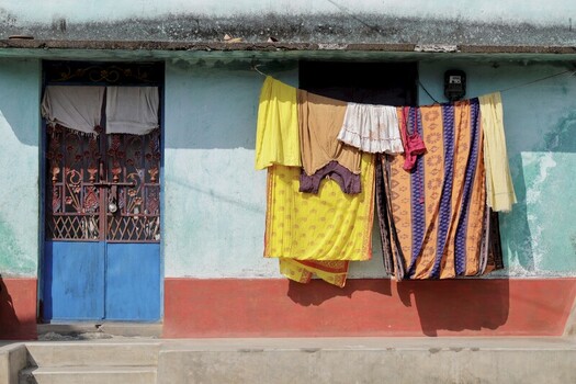 Odisha India 26 March 2026 View of a vibrant blue door contrasting with the soft teal walls while laundry dries in the sun against the textured facade. Odisha India 26 March 2026 View of a vibrant blue door contrasting with the soft teal walls while laundry dries in the sun against the textured facade.