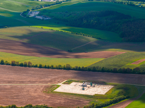 Aerial view of agricultural fields and rolling hills with a small industrial site in the countryside of Brno South Moravian Region Czechia.