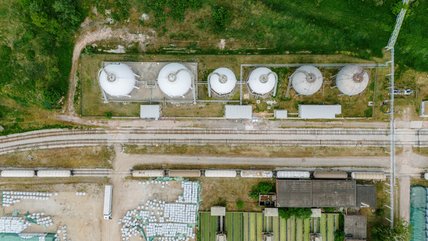 Aerial view of large white spherical storage tanks railway tracks with freight wagons and industrial infrastructure surrounded by green vegetation in Sabac Vojvodina Serbia. Aerial view of large white spherical storage tanks railway tracks with freight wagons and industrial infrastructure surrounded by green vegetation in Sabac Vojvodina Serbia.