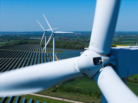 Aerial view of Chelveston Wind Farm featuring wind turbines and solar panels across green fields under a clear blue sky Wellingborough England United Kingdom. Aerial view of Chelveston Wind Farm featuring wind turbines and solar panels across green fields under a clear blue sky Wellingborough England United Kingdom.