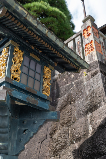 View of an ornate lantern with golden dragons contrasting against weathered stone steps under a canopy of green foliage Narita Chiba Japan. View of an ornate lantern with golden dragons contrasting against weathered stone steps under a canopy of green foliage Narita Chiba Japan.