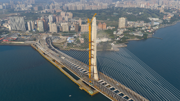 Aerial view of the Danjiang Bridge under construction with its tall pylon and cable stayed design spanning the Tamsui River near the skyline of Tamsui District New Taipei City Taiwan.
