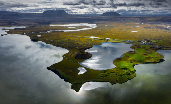 Aerial view of volcanic pseudocraters and the calm waters of Lake Myvatn reflecting a dramatic cloudy sky Iceland.