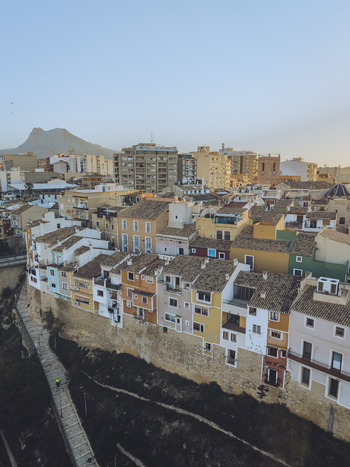 Aerial view of colorful houses built along a stone wall with a mountain peak in the distance under a clear sky La Vila Joiosa Valencian Community Spain. Aerial view of colorful houses built along a stone wall with a mountain peak in the distance under a clear sky La Vila Joiosa Valencian Community Spain.