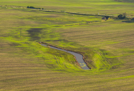 Aerial view of a small pond nestled within the rolling green fields of the Kashubia region in Pelplin Pomeranian Voivodeship Poland.