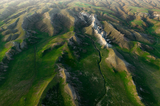 Aerial view of the Airakty mountains featuring dramatic limestone ridges rolling green hills and deep valleys under soft light in Shetpe Mangystau Region Kazakhstan.