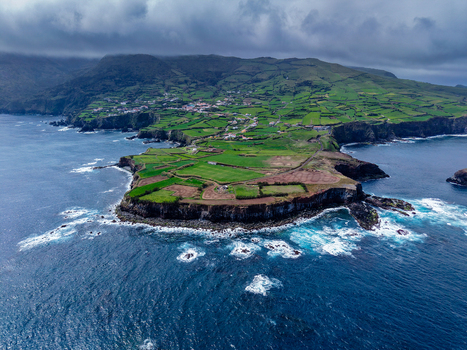 Aerial view of verdant cliffs meet the turbulent Atlantic the island s edge a tapestry of emerald fields and rugged coastline Flores A&ccedil;ores Portugal.