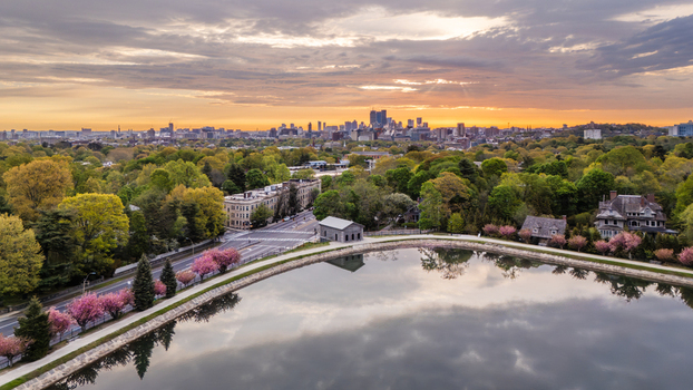 Aerial view of Brookline Reservoir surrounded by blooming cherry blossoms and lush greenery with the Boston skyline at sunrise in Brookline Massachusetts United States.