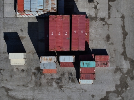 Aerial view of stacked shipping containers in various colors on a weathered asphalt lot with long shadows Cincinnati OH United States.