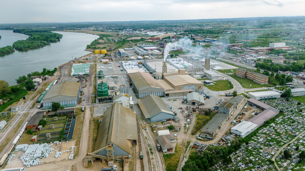 Aerial view of an industrial complex with large warehouses and smoking chimneys near the Sava River in Sabac Vojvodina Serbia. Aerial view of an industrial complex with large warehouses and smoking chimneys near the Sava River in Sabac Vojvodina Serbia.