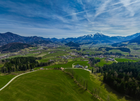 Aerial view of lush green fields meeting dense forests under a vast sky with distant snow capped mountains Windischgarsten Upper Austria Austria. Aerial view of lush green fields meeting dense forests under a vast sky with distant snow capped mountains Windischgarsten Upper Austria Austria.