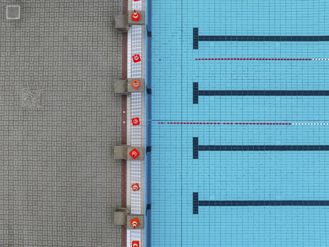 Aerial view of a tranquil public swimming pool with organized blue tiles and geometric patterns Mariendorf Germany.