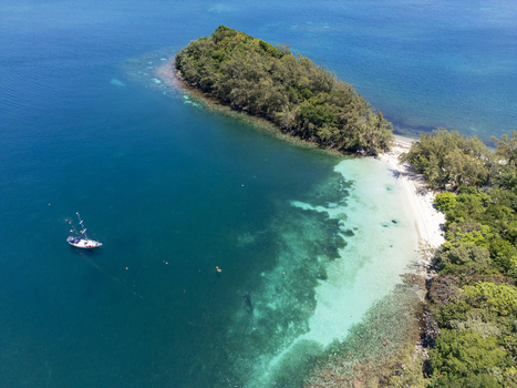 Aerial view of a lush tropical island with white sand beaches and turquoise waters under a bright sun Guanaja Bay Islands Department Honduras. Aerial view of a lush tropical island with white sand beaches and turquoise waters under a bright sun Guanaja Bay Islands Department Honduras.