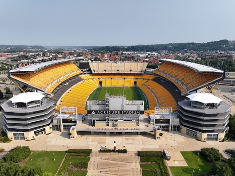 Pittsburgh United States 26 July 2026 Aerial view of Acrisure Stadium with its yellow seating green field and surrounding urban landscape under a clear sky.