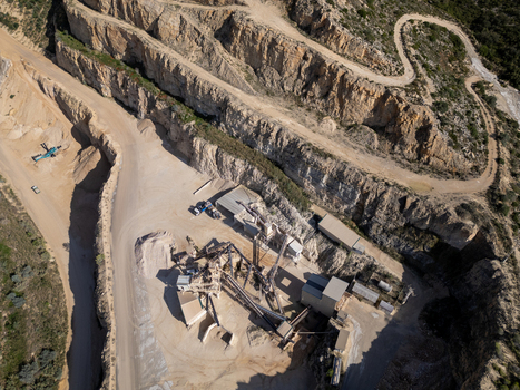 Aerial view of a stone quarry with industrial machinery conveyor belts and terraced rock walls Teulada Valencian Community Spain.