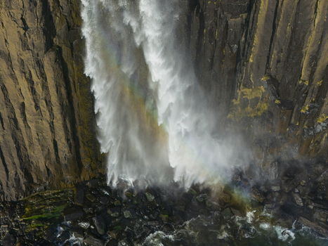 Aerial view of Kilt Rock and Mealt Falls cascading down basalt cliffs into the sea with a rainbow in the mist Isle of Skye Scotland United Kingdom. Aerial view of Kilt Rock and Mealt Falls cascading down basalt cliffs into the sea with a rainbow in the mist Isle of Skye Scotland United Kingdom.