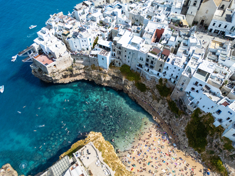 Aerial view of the historic town of Polignano a Mare with white buildings perched on limestone cliffs above the turquoise waters of Lama Monachile beach in Polignano a Mare Apulia Italy. Aerial view of the historic town of Polignano a Mare with white buildings perched on limestone cliffs above the turquoise waters of Lama Monachile beach in Polignano a Mare Apulia Italy.
