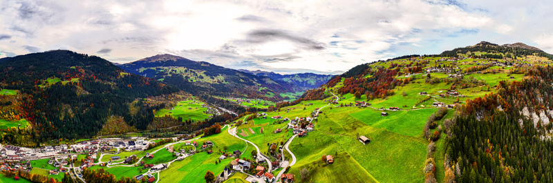 Aerial view of the village of Klosters Serneus with traditional chalets winding roads and autumn foliage on the surrounding slopes in Klosters Serneus Grisons Switzerland.
