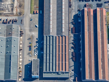 Aerial view of industrial buildings casting long shadows under a bright sky geometric patterns and textures of rooftops Sausheim Grand Est France.