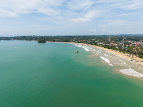 Aerial view of the turquoise waters of Weligama Bay and the sandy coastline with coastal buildings Weligama Southern Province Sri Lanka.