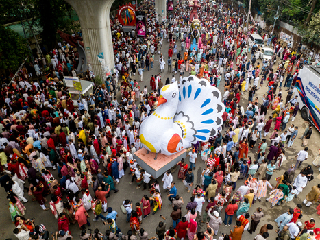 Dhaka Bangladesh 13 April 2026 Aerial view of a vibrant sea of people surrounding a colossal colorful bird float under an elevated structure.