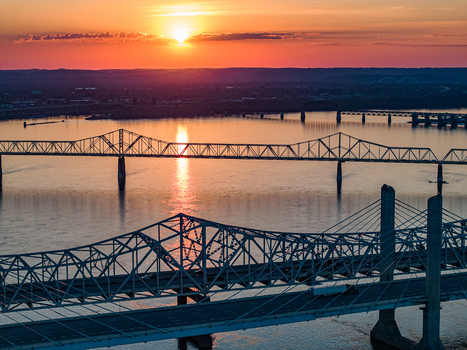 Aerial view of multiple bridges spanning the Ohio River during a vibrant sunset with orange sky reflections in Louisville Kentucky United States. Aerial view of multiple bridges spanning the Ohio River during a vibrant sunset with orange sky reflections in Louisville Kentucky United States.