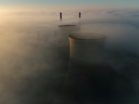 Aerial view of the RWE Clauscentrale power plant cooling towers and chimneys emerging from a thick layer of morning fog in Maasbracht Limburg Netherlands. Aerial view of the RWE Clauscentrale power plant cooling towers and chimneys emerging from a thick layer of morning fog in Maasbracht Limburg Netherlands.