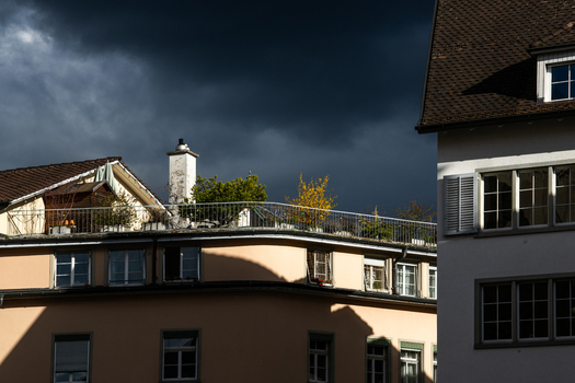 Zurich Switzerland 02 April 2023 View of rooftops basking in golden light contrasting sharply with the ominous dark storm clouds looming above the city s skyline. Zurich Switzerland 02 April 2023 View of rooftops basking in golden light contrasting sharply with the ominous dark storm clouds looming above the city s skyline.