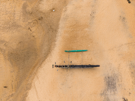 Aerial view of a traditional wooden outrigger boat resting on the golden sand of a tropical beach in Galle Southern Province Sri Lanka.