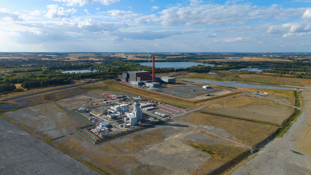 Aerial view of Millbrook Power Plant featuring industrial infrastructure storage tanks and a tall chimney set within a landscape of open fields and lakes in Stewartby England United Kingdom. Aerial view of Millbrook Power Plant featuring industrial infrastructure storage tanks and a tall chimney set within a landscape of open fields and lakes in Stewartby England United Kingdom.