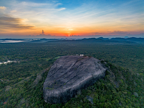 Aerial view of Pidurangala Rock surrounded by lush green forest under a vibrant sunset sky in Sigiriya Central Province Sri Lanka. Aerial view of Pidurangala Rock surrounded by lush green forest under a vibrant sunset sky in Sigiriya Central Province Sri Lanka.