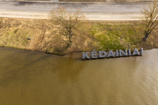 Kedainiai Lithuania 17 March 2026 Aerial view of the city name sign Kedainiai placed in the river water next to a grassy bank and a road. Kedainiai Lithuania 17 March 2026 Aerial view of the city name sign Kedainiai placed in the river water next to a grassy bank and a road.