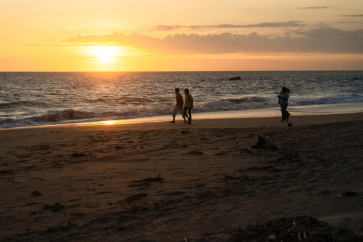 Sri Lanka 11 January 2026 View of people walking along the sandy beach during a golden sunset.