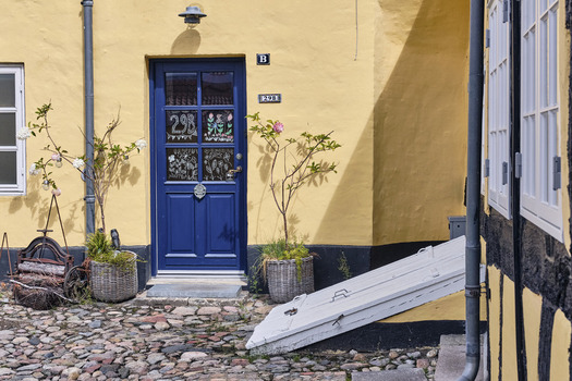 Viborg Denmark 07 August 2026 View of a traditional yellow timber framed house with a blue door and cobblestone courtyard in the historic old town. Viborg Denmark 07 August 2026 View of a traditional yellow timber framed house with a blue door and cobblestone courtyard in the historic old town.