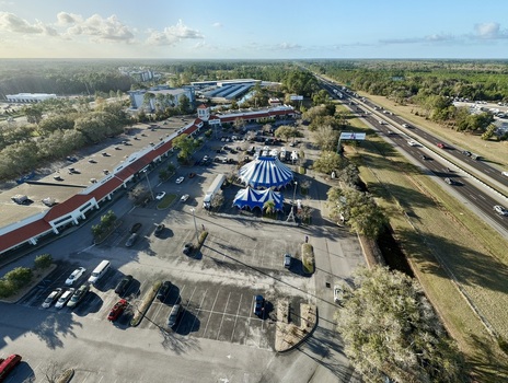 Aerial view of a vibrant blue and white circus tent standing boldly against the muted tones of a parking lot and a busy highway St. Augustine Florida United States. Aerial view of a vibrant blue and white circus tent standing boldly against the muted tones of a parking lot and a busy highway St. Augustine Florida United States.