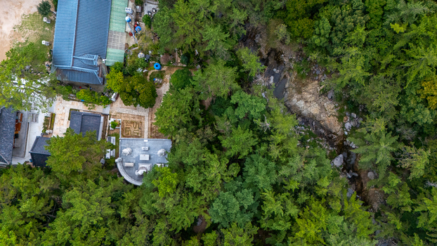 Aerial view of a traditional Korean temple complex nestled within a dense forest featuring tiled roofs stone courtyards and a small stream in Busan Busan South Korea. Aerial view of a traditional Korean temple complex nestled within a dense forest featuring tiled roofs stone courtyards and a small stream in Busan Busan South Korea.