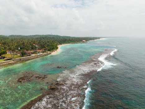 Aerial view of Thalpe Beach with turquoise waters a coral reef barrier and lush palm trees lining the shoreline Talpe Southern Province Sri Lanka. Aerial view of Thalpe Beach with turquoise waters a coral reef barrier and lush palm trees lining the shoreline Talpe Southern Province Sri Lanka.