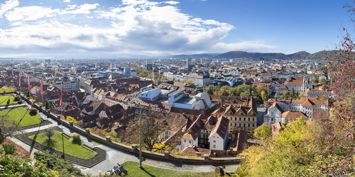View of the city s rooftops cascade under a bright sky showcasing a blend of urban sprawl and natural beauty with trees in full autumn colors Graz Styria Austria. View of the city s rooftops cascade under a bright sky showcasing a blend of urban sprawl and natural beauty with trees in full autumn colors Graz Styria Austria.