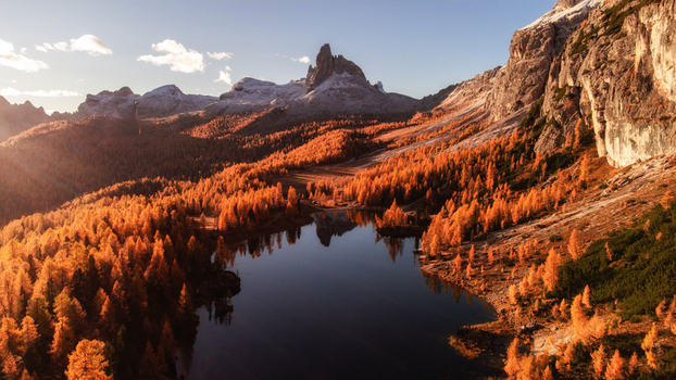 Aerial view of Lago Federa surrounded by vibrant autumn larch forests and dramatic Dolomite mountain peaks under golden hour light in Cortina d Ampezzo Veneto Italy. Aerial view of Lago Federa surrounded by vibrant autumn larch forests and dramatic Dolomite mountain peaks under golden hour light in Cortina d Ampezzo Veneto Italy.