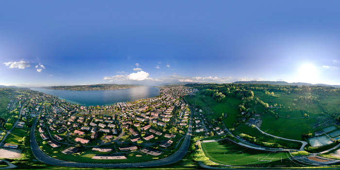 Aerial view of the residential area of Thalwil overlooking Lake Zurich with green hills and a football field under a clear blue sky Thalwil Zurich Switzerland.