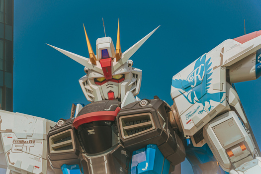 View of the life sized Freedom Gundam statue at Lalaport featuring mechanical details white and blue armor plating and a clear blue sky Shanghai Shanghai China.