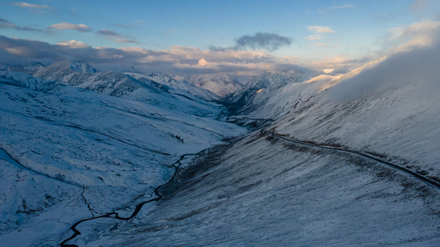 Aerial view of Babusar Pass with a winding road and a river flowing through the snow covered valley under a cloudy sky Babusar KPK Pakistan. Aerial view of Babusar Pass with a winding road and a river flowing through the snow covered valley under a cloudy sky Babusar KPK Pakistan.
