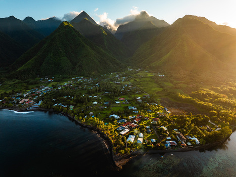 Aerial view of lush green volcanic mountains and a coastal village during golden hour Moorea Maiao Windward Islands French Polynesia. Aerial view of lush green volcanic mountains and a coastal village during golden hour Moorea Maiao Windward Islands French Polynesia.