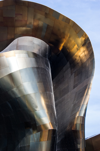 View of the metallic curved exterior of the Museum of Pop Culture with its distinctive shimmering panels against a clear blue sky in Seattle Washington United States.