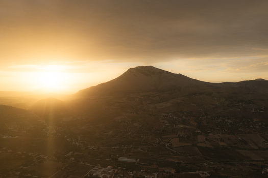 Aerial view of Riserva Naturale Orientata dello Zingaro at sunset with golden light illuminating the rugged mountain peaks and rolling hills in San Vito Lo Capo Sicilia Italy. Aerial view of Riserva Naturale Orientata dello Zingaro at sunset with golden light illuminating the rugged mountain peaks and rolling hills in San Vito Lo Capo Sicilia Italy.