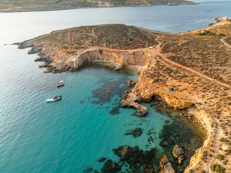 Aerial view of turquoise waters meet rugged coastline boats bob gently near the shore a serene escape under the vast sky Blue lagoon Comino Malta. Aerial view of turquoise waters meet rugged coastline boats bob gently near the shore a serene escape under the vast sky Blue lagoon Comino Malta.