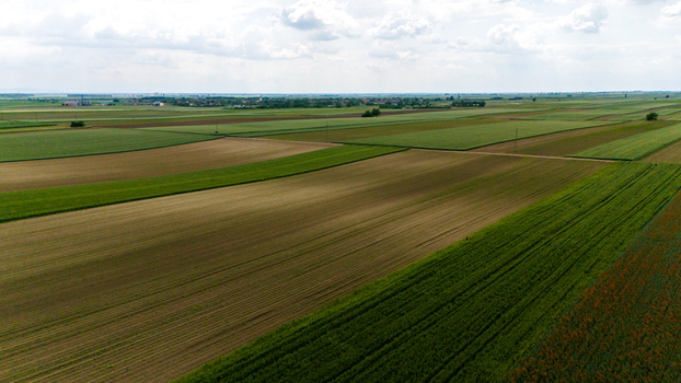 Aerial view of vast agricultural fields and fertile farmlands under a cloudy sky near the horizon Novi Sad Vojvodina Serbia. Aerial view of vast agricultural fields and fertile farmlands under a cloudy sky near the horizon Novi Sad Vojvodina Serbia.