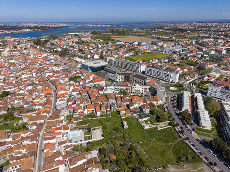 Aerial view of sun drenched terracotta roofs meet modern architecture bisected by roads and verdant green spaces Póvoa de Varzim Portugal. Aerial view of sun drenched terracotta roofs meet modern architecture bisected by roads and verdant green spaces Póvoa de Varzim Portugal.