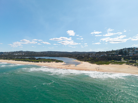 Aerial view of the Northern Beaches coastline featuring a sandy beach turquoise ocean waves a lagoon and residential houses on the hills Northern Beaches Council New South Wales Australia.